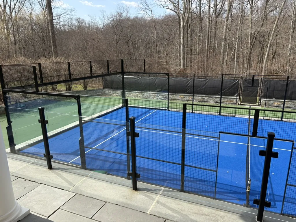 Blue panoramic padel court built on part of an existing tennis court at a private residence in Greenwich, Connecticut